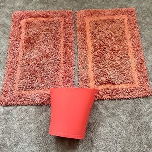 Beautiful coral rugs and trash can.